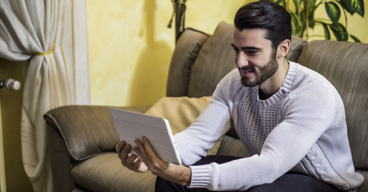 Man in home looking at tablet smiling