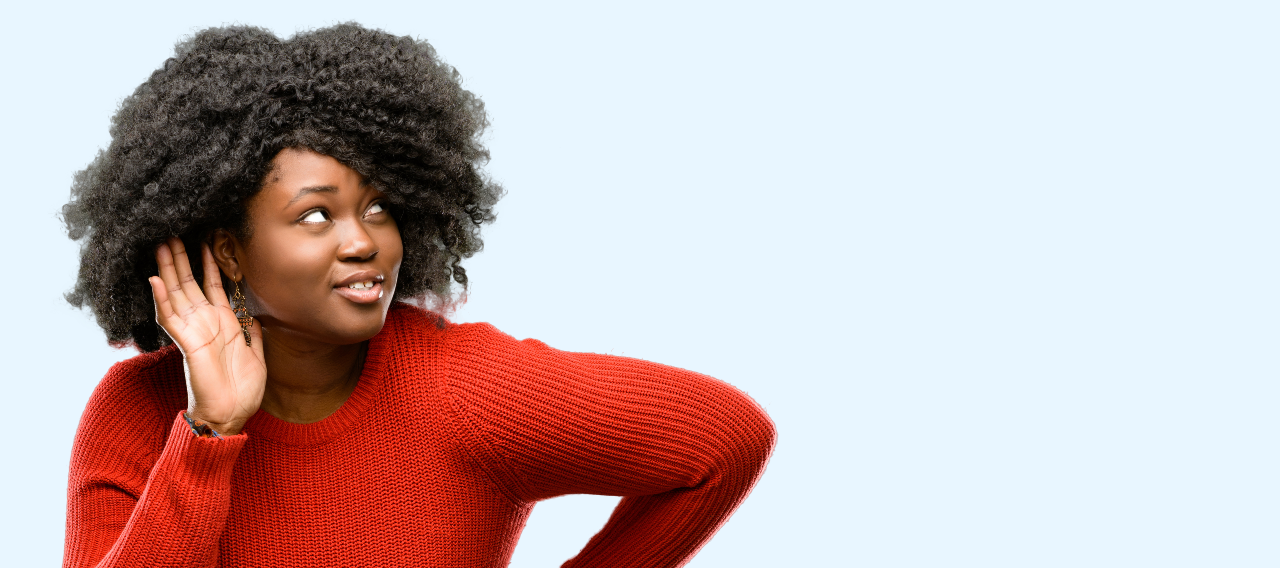 African American woman holding hand to her ear leaning forward on a blue background